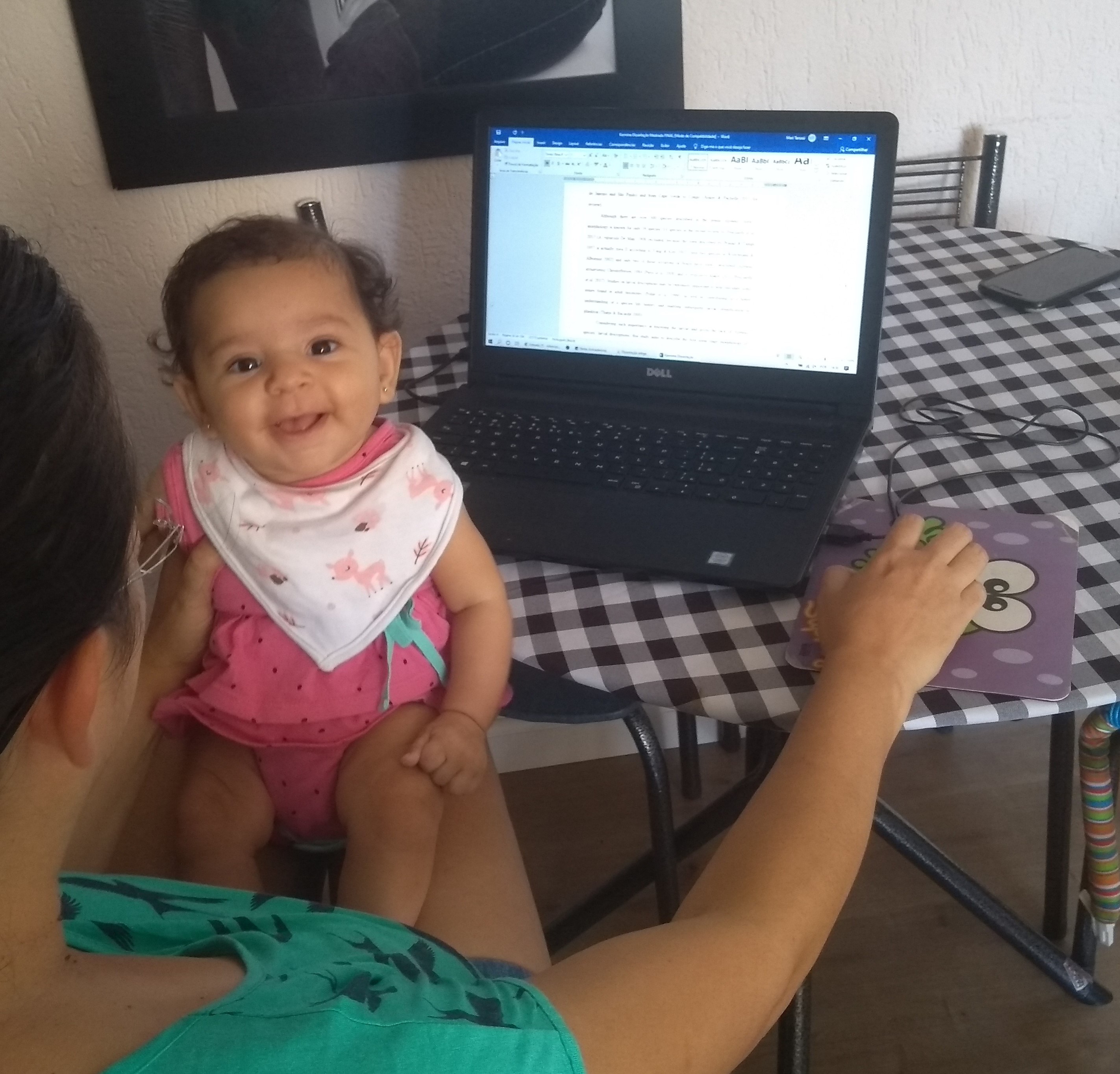 pesquisadora escreve no computador com filha no colo