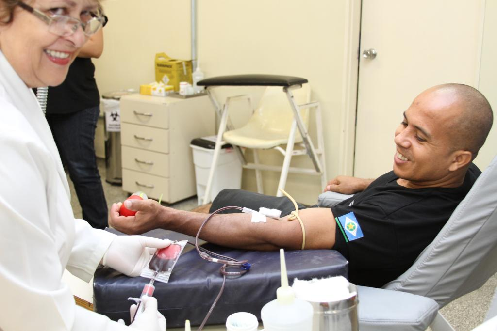 Homem realizando doação de sangue ao lado de uma enfermeira.