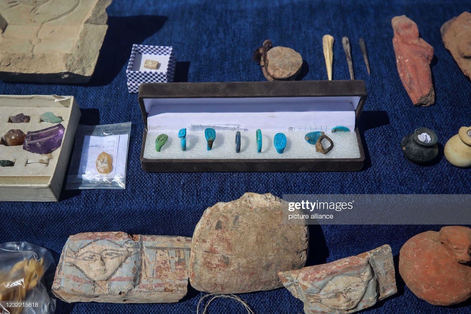 Imagem dos artefatos encontados em outro ângulo, montrando jóias de pedras coloridas e desenhos em pedras.