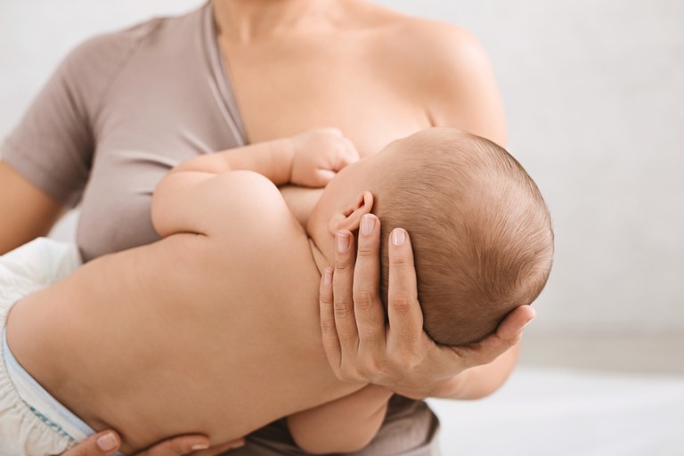 Mulher amamentando um bebê em seu colo.